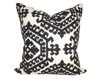 May include: Black and white geometric patterned throw pillow with a white background and black embroidery.