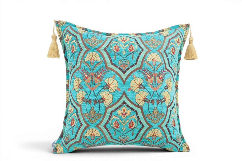 May include: A square throw pillow in a vibrant turquoise fabric featuring a repeating dark brown geometric lattice pattern filled with stylized floral motifs in shades of cream, red, and orange. The pillow is finished with beige tassels.