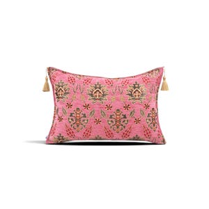 Op de afbeelding: Een roze rechthoekig sierkussen met een sierlijk bloemmotief in bruin, goud en rood. Het kussen heeft een textuur en is afgewerkt met twee beige kwastjes. Dit decoratieve kussen voegt een vleugje elegantie toe aan elke kamer. Afmetingen: ongeveer 40 cm x 60 cm.
