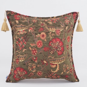 May include: A green and red floral patterned throw pillow with tassels on each corner.