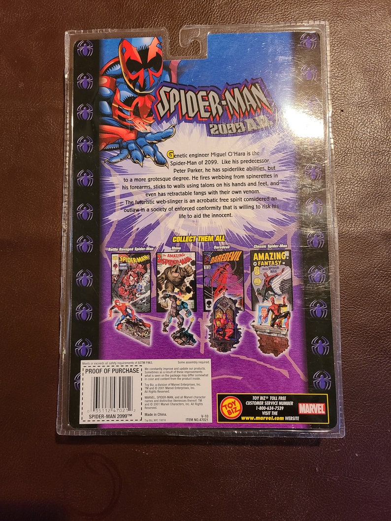 May include: A red and black Spider-Man 2099 action figure with a red and black comic book cover background. The figure is posed with its arms outstretched and its legs bent. The figure is holding a web shooter in its right hand. The comic book cover features a red and black Spider-Man 2099 character with a red and black background. The comic book cover also features the text "Amazing! Fantasy Spider-Man".
