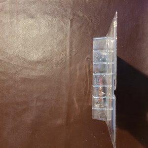 May include: A clear plastic blister pack containing a small toy figure. The figure is partially visible and appears to be made of plastic.