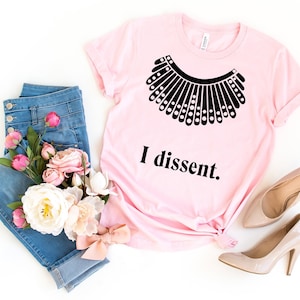 May include: Pink t-shirt with a black silhouette of a judge's collar and the text "I dissent."