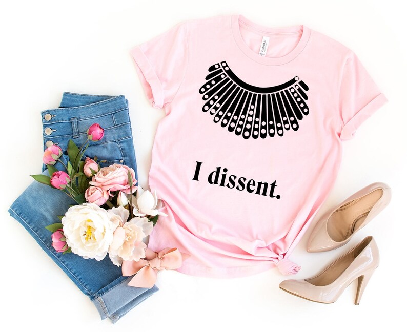 May include: Pink t-shirt with a black silhouette of a judge's collar and the text "I dissent."