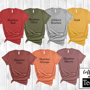 Puede incluir: Un conjunto de diez camisetas en varios colores jaspeado, incluyendo rojo, oliva, gris, dorado, arcilla, naranja y malva. Cada camiseta tiene un color diferente y presenta el texto "Heather" seguido del nombre del color.