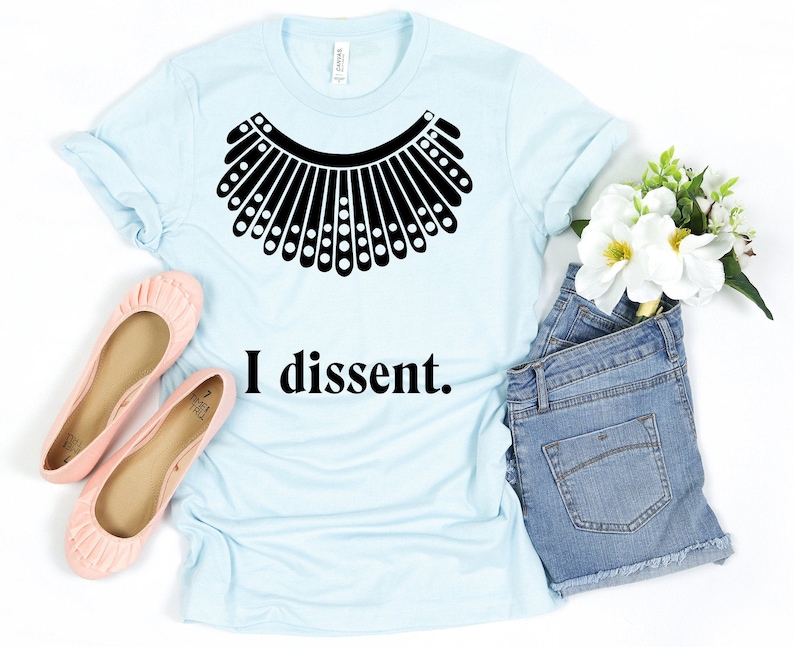 May include: A light blue t-shirt with a black graphic of a judge's collar and the text "I dissent."