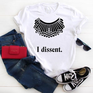 May include: White t-shirt with a black silhouette of a judge's collar and the text "I dissent."