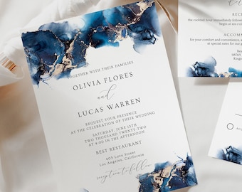 Op de afbeelding: Een trouwuitnodigingsset met een hoofduitnodiging, een detailkaart en een RSVP-kaart. Het ontwerp bevat een blauw en goud abstract aquarelpatroon. De tekst bevat de namen Olivia Flores en Lucas Warren en huwelijksdetails.