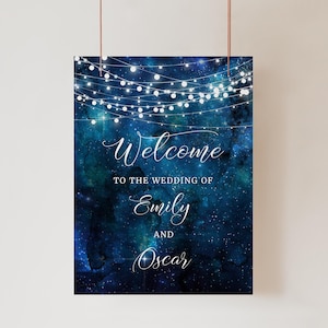 May include: A blue and white wedding welcome sign with a galaxy background and white string lights. The text reads "Welcome to the wedding of Emily and Oscar".