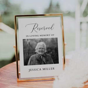 Puede incluir: Un letrero conmemorativo con marco dorado con la palabra "Reserved" en escritura elegante. Debajo, el texto dice "IN LOVING MEMORY OF" encima de una foto en blanco y negro de una mujer. El nombre "JESSICA MILLER" está impreso en la parte inferior.