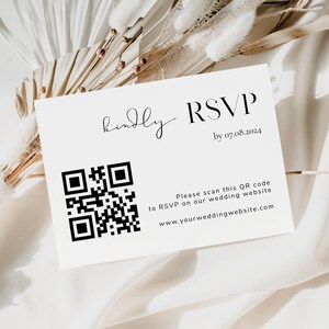 May include: A white RSVP card with a black and white QR code. The text on the card reads "Kindly RSVP by 07.08.2024. Please scan this QR code to RSVP on our wedding website www.yourweddingwebsite.com"