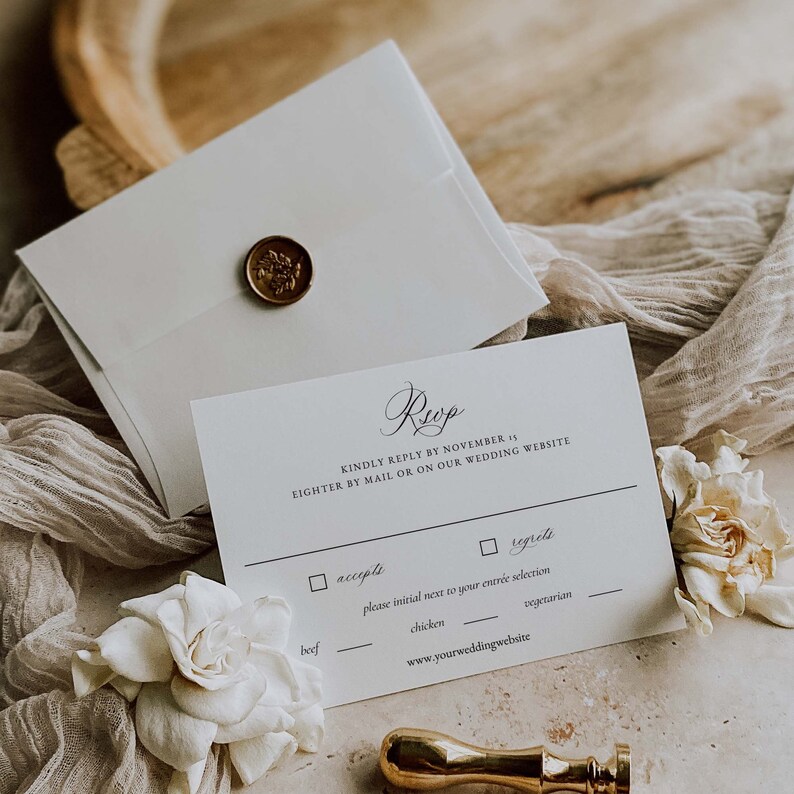 May include: A white RSVP card with black text. The text reads "Rup" in cursive, "Kindly reply by November 15, eigher by mail or on our wedding website." There are two checkboxes, one for "accepts" and one for "regrets". Below the checkboxes is a line with the text "please initial next to your entree selection." There are three options for entree: beef, chicken, and vegetarian.