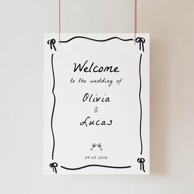 May include: A white wedding welcome sign with a black hand-drawn border. The sign says "Welcome to the wedding of Olivia & Lucas" and "04.05.2026".