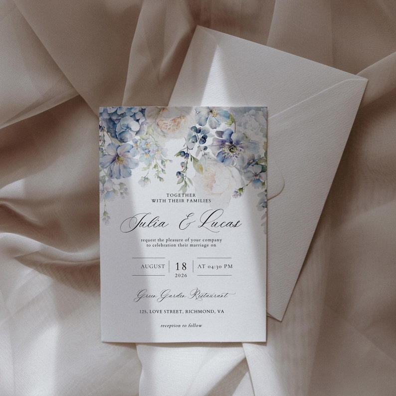 Puede incluir: Una invitaci&oacute;n de boda con un dise&ntilde;o floral de acuarela en tonos azules y blancos. La invitaci&oacute;n presenta los nombres "Julia & Lucas" y la fecha "18 de agosto de 2026" a las 4:30 PM. El lugar es "Green Garden Restaurant" ubicado en 125 Love Street, Richmond, VA. La invitaci&oacute;n tambi&eacute;n incluye el texto "recepci&oacute;n a seguir".