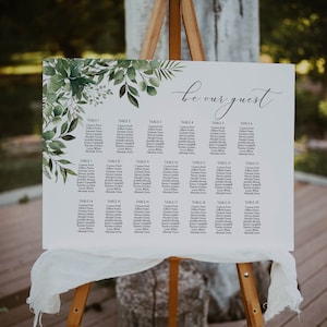 May include: A wedding seating chart with a leafy green watercolour background. The chart is titled "be our guest" and lists guest names by table number.