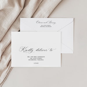May include: A white envelope with a black handwritten inscription that reads "Kindly deliver to" followed by a name and address. The envelope is on a beige surface.