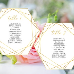 Puede incluir: Dos tarjetas de mesa hexagonales blancas con líneas geométricas doradas y el texto "mesa 1" y "mesa 2" con una lista de nombres debajo de cada número de mesa.