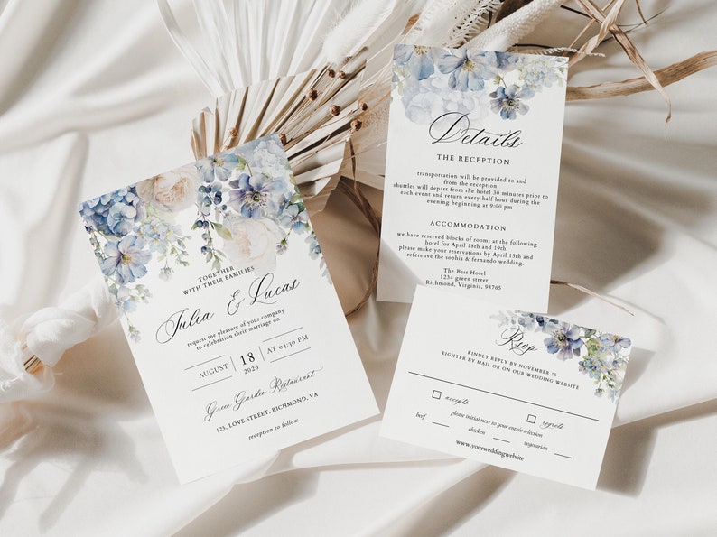 Puede incluir: Conjunto de invitaciones de boda con dise&ntilde;os florales azules. La tarjeta de invitaci&oacute;n presenta los nombres "Julia & Lucas" y la fecha "18 de agosto de 2026". La tarjeta de detalles de la recepci&oacute;n incluye informaci&oacute;n sobre el transporte, el alojamiento y los detalles de la respuesta.