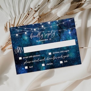 May include: A blue and white RSVP card with a starry night sky background and string lights. The text reads "kindly reply by November 10". There are checkboxes for accepting or declining the invitation and for choosing a meal option: beef, chicken, or fish.