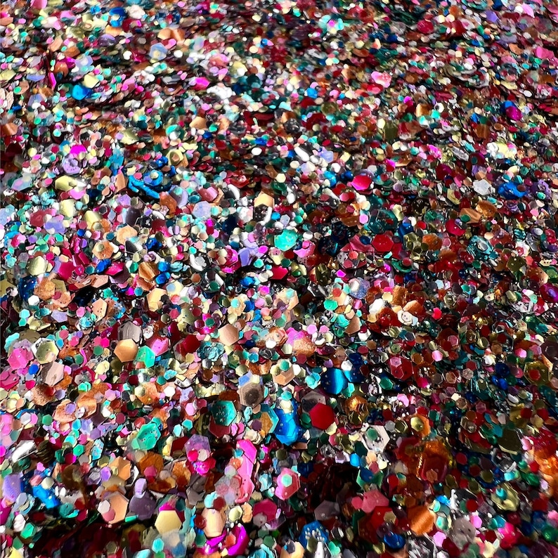 May include: Close-up of a pile of colorful glitter. The glitter pieces are various shapes and sizes, including hexagons and circles. Colors include red, pink, blue, green, gold, and silver. The glitter has a shiny, reflective quality.