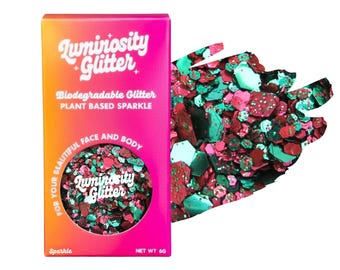 May include: A rectangular box of Luminosity Glitter with a pink and orange gradient, featuring the text Biodegradable Glitter, Plant Based Sparkle, and Net Wt 6g. A circular cutout reveals a mix of metallic red and teal hexagonal glitter particles.