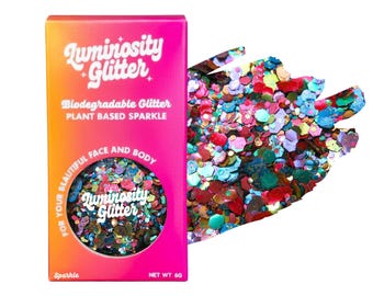 May include: A box of Luminosity Glitter in a gradient orange and pink box with the text "Biodegradable Glitter, Plant Based Sparkle". The box contains colorful glitter for face and body. A swatch of the glitter is next to the box.