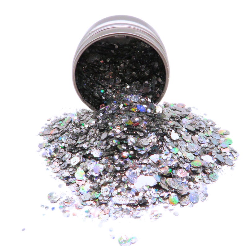 May include: A silver glitter mix with iridescent flakes in a silver container. The glitter is spilling out of the container.