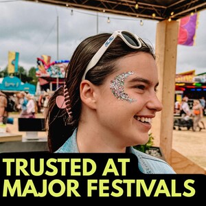 May include: A smiling person with glitter makeup in a crescent moon shape on their face. They are wearing sunglasses with the text "The Hut" on the frame. The text "TRUSTED AT MAJOR FESTIVALS" is displayed in a black banner at the bottom of the image.