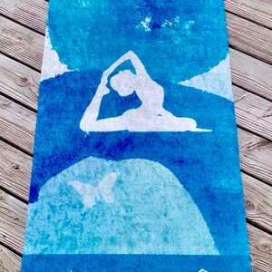 May include: A rectangular yoga mat with a blue watercolor design and white yoga poses. The mat features a gradient of blue hues, with white silhouettes of yoga figures. The text "SUNRISE YOGA" is at the bottom.