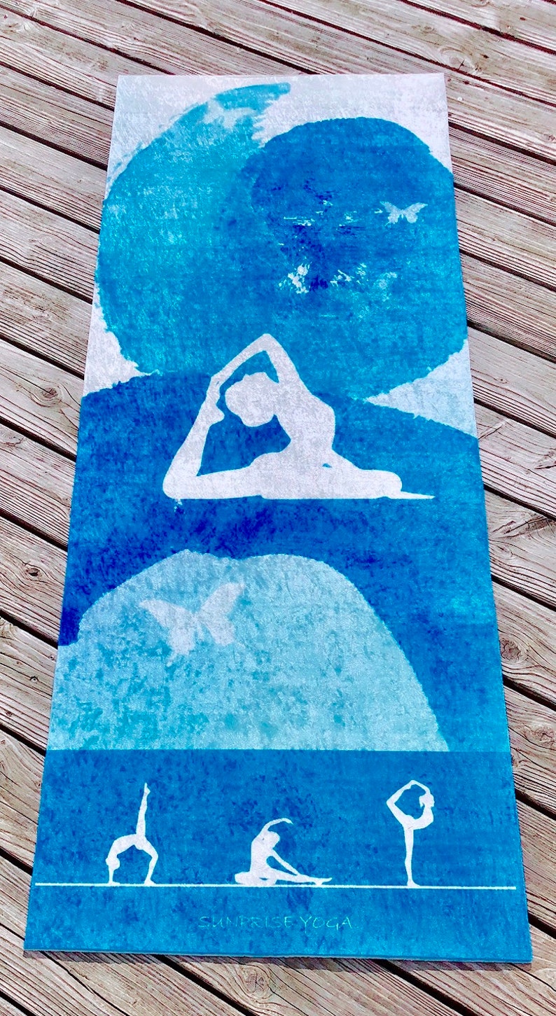May include: A rectangular yoga mat with a blue watercolor design and white yoga poses. The mat features a gradient of blue hues, with white silhouettes of yoga figures. The text "SUNRISE YOGA" is at the bottom.