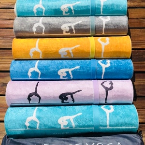 May include: Rolled yoga mats in various colors, including blue, gray, yellow, and purple, each featuring a white yoga pose design. The mats are secured with matching straps. A dark gray bag with "SUNPRISE YOGA" is at the bottom.