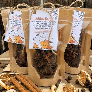 May include: Three brown paper pouches filled with dried spices, each featuring a white tag labeled Witches Brew with instructions to add two cups of water and simmer. The tags display illustrations of ghosts, pumpkins, and spiderwebs.
