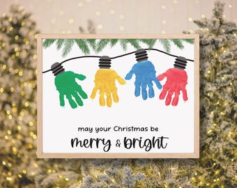 Può includere: Stampa incorniciata con lampadine a forma di impronta di mani verdi, gialle, blu e rosse. Le lampadine sono collegate da un filo nero, con aghi di pino verdi sopra. Il testo recita "may your Christmas be merry & bright".
