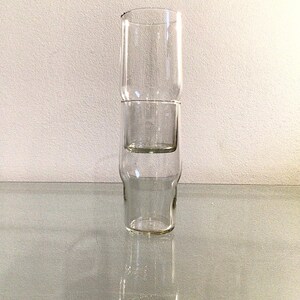 May include: Three clear glass cups stacked on top of each other. The cups are all the same size and shape, and they are made of a clear glass.