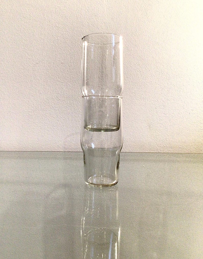 May include: Three clear glass cups stacked on top of each other. The cups are all the same size and shape, and they are made of a clear glass.