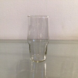May include: A clear glass drinking glass with a wide base and a slightly flared top.