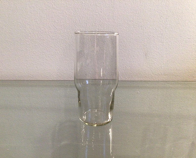 May include: A clear glass drinking glass with a wide base and a slightly flared top.