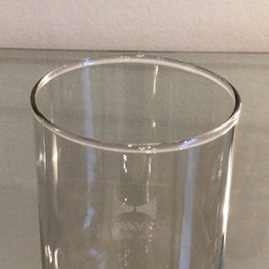 May include: A clear glass drinking glass with a wide mouth and a straight, cylindrical shape.