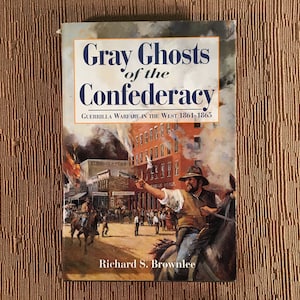May include: Book cover with a painting of a man on horseback firing a gun in a town during a fire. The title of the book is "Gray Ghosts of the Confederacy: Guerrilla Warfare in the West 1861-1865" by Richard S. Brownlee.