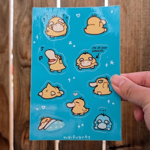 Puede incluir: Una hoja de pegatinas azules con un personaje de dibujos animados con diferentes expresiones. El personaje es amarillo con la nariz y los ojos marrones. Las pegatinas tienen un texto que dice "ate all your pokeballs".