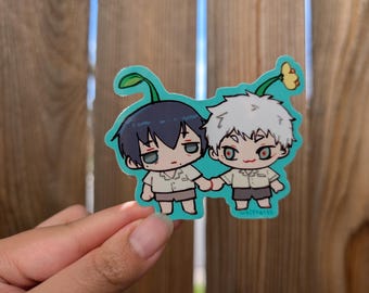 May include: A teal sticker featuring two anime-style characters holding hands. One character has dark blue hair and the other has white hair. Both have sprouts on their heads and are wearing tan shirts and shorts.