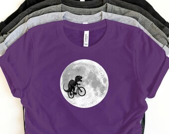 Funny Dinosaur Bicycle T-Shirt | T-Rex Riding Bike Graphic Tee | Novelty Moon Print Shirt