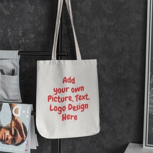 K&ouml;nnte beinhalten: Wei&szlig;e Stofftasche mit rotem Text, der "F&uuml;gen Sie Ihr eigenes Bild, Text, Logo Design hier ein" lautet.