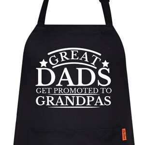 以下が含まれることがあります： 「Great Dads Get Promoted to Grandpas」という白い文字が書かれた黒いエプロン。