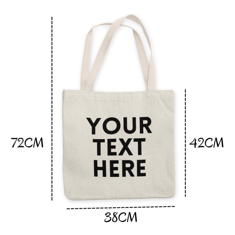 K&ouml;nnte beinhalten: Eine wei&szlig;e Canvas-Tragetasche mit schwarzen Henkeln und dem aufgedruckten Text "YOUR TEXT HERE" auf der Vorderseite. Die Tasche ist 38 cm breit, 42 cm hoch und 7,5 cm tief.