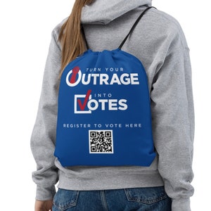 May include: Blue drawstring backpack with the text "TURN YOUR OUTRAGE INTO VOTES" in white and red. Below the text is a QR code and the words "REGISTER TO VOTE HERE" in white. The backpack has black drawstrings.