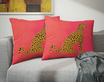 May include: Two pink throw pillows with a cheetah print design. The cheetah is sitting down and is facing to the right. The pillows are on a gray couch.