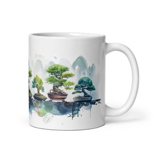 May include: White ceramic mug with a watercolor design of four bonsai trees in pots against a background of mountains and clouds.