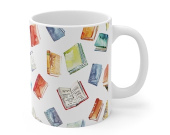 Puede incluir: Taza de cerámica blanca con un patrón de acuarela colorido de libros abiertos y cerrados. Los libros están en varios tonos de azul, verde, rojo, naranja y amarillo.