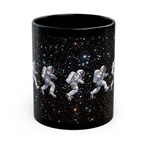 Könnte beinhalten: Schwarze Kaffeetasse mit einem Design von Astronauten, die im Weltraum auf einem sternenübersäten Hintergrund spazieren gehen.